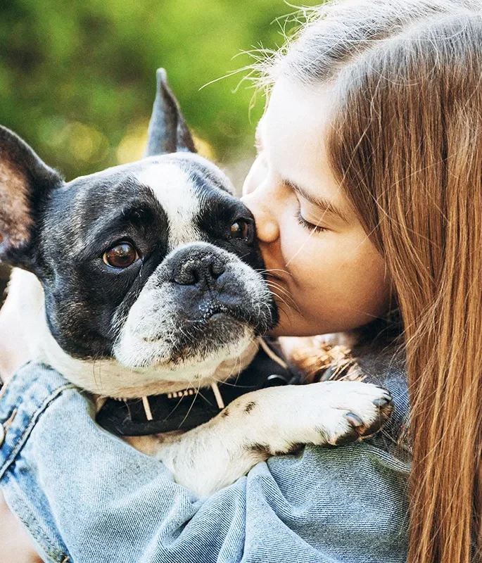 A girl kissing her French bulldog